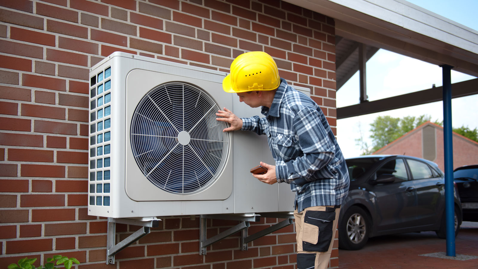 Man wearing hard hat inspecting air source heat pump