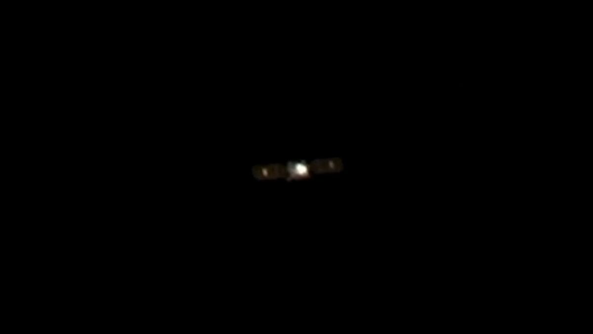 photo of a cube-shaped satellite in deep space, taken from a distance by another satellite