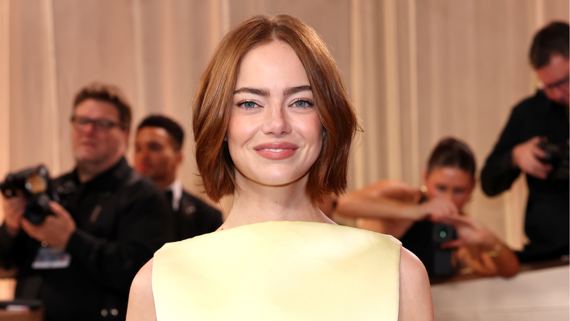 Emma Stone wearing a bob haircut to the golden globes. She is also wearing a yellow sleeveless top. 
