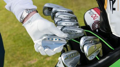 A hand picking out a Callaway wedge from a golf bag