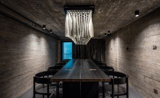 The dining room features a table designed by the architects and a bespoke chandelier with fabric that directs light towards
