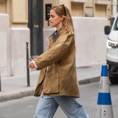 Emma Watson steps out in Paris wearing a barn jacket in a light brown shade with straight-leg jeans and Birkenstock mules.