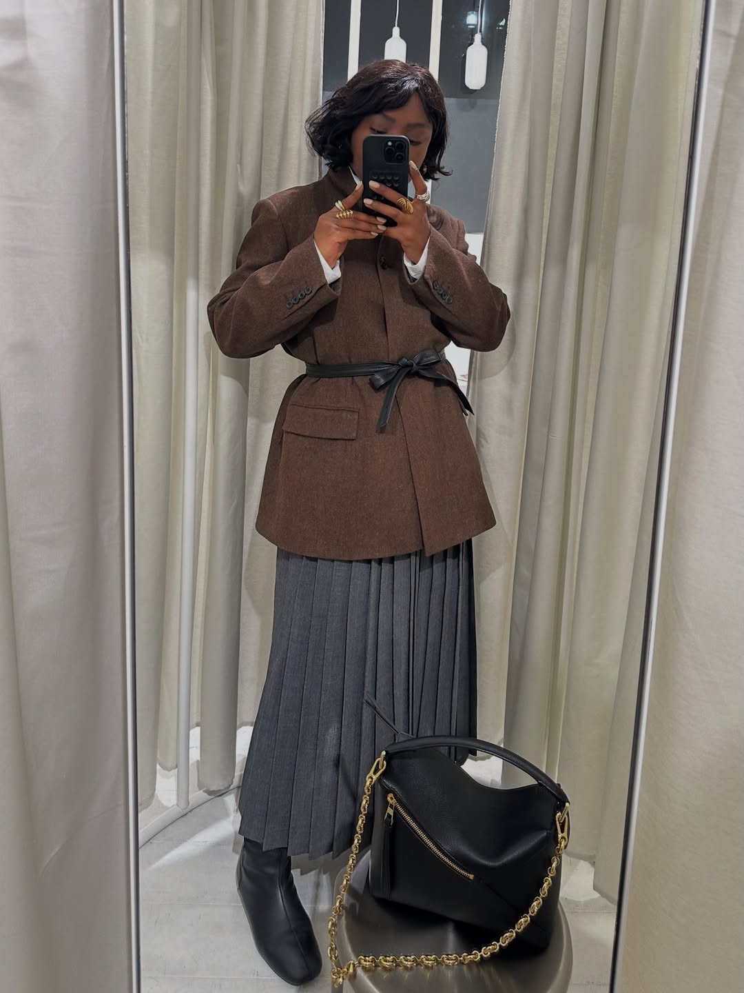 Influencer Frann Fyne wearing anti-trend outfit of blazer with pleated skirt and knee-high boots.