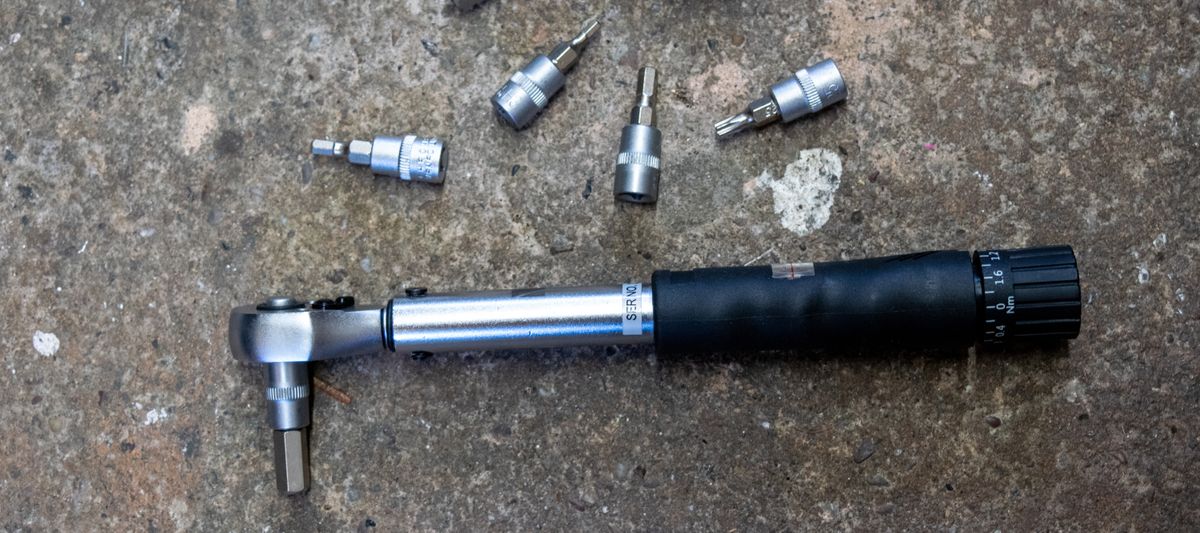 An M Part torque wrench and hex bits on a concrete floor 