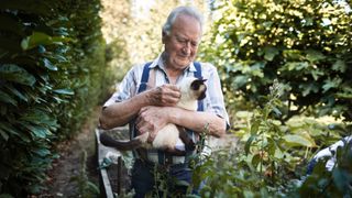 Man holding his cat in the garden
