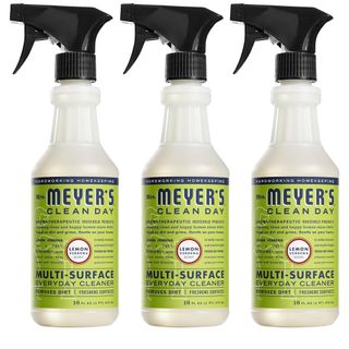 Three side-on clear bottles of cleaning spray with black spray lids and bright green and navy labels