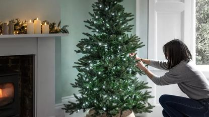 Woman putting lights on a Christmas tree during the festive period