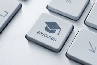 Close of of computer key labeled &quot;education&quot; with graduation cap and mortarboard.