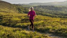 Woman training for a marathon, running on hilltop in the countryside