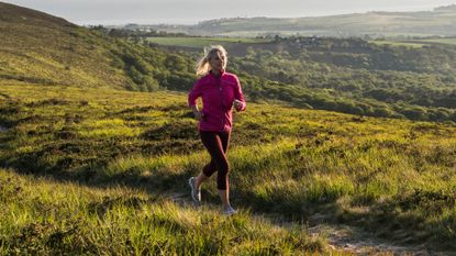 Woman training for a marathon, running on hilltop in the countryside