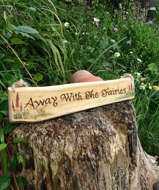 wooden 'away with the fairies' sign in a garden