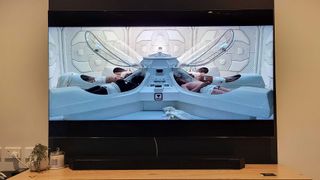 En Samsung QN900B Neo QLED 8K TV står på en liten TV-bänk och spelar upp en sci-fi-film.