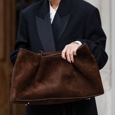 A woman clutching a brown suede bag with a brown manicure, a key winter nail trend