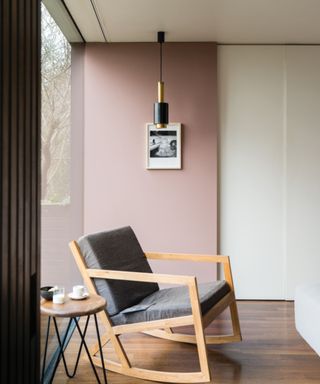 living area with pink accent wall, wooden flooring and wooden armchair