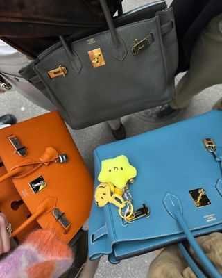 three Hermès Birkin bags in orange, blue, and grey