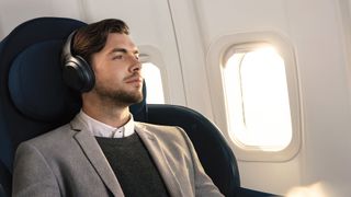 A man wearing the sony wh-1000xm3 wireless headphones while relaxing on a flight