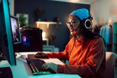 A person gaming using a PC and wearing a headset