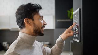 A man with smart home controls in the kitchen