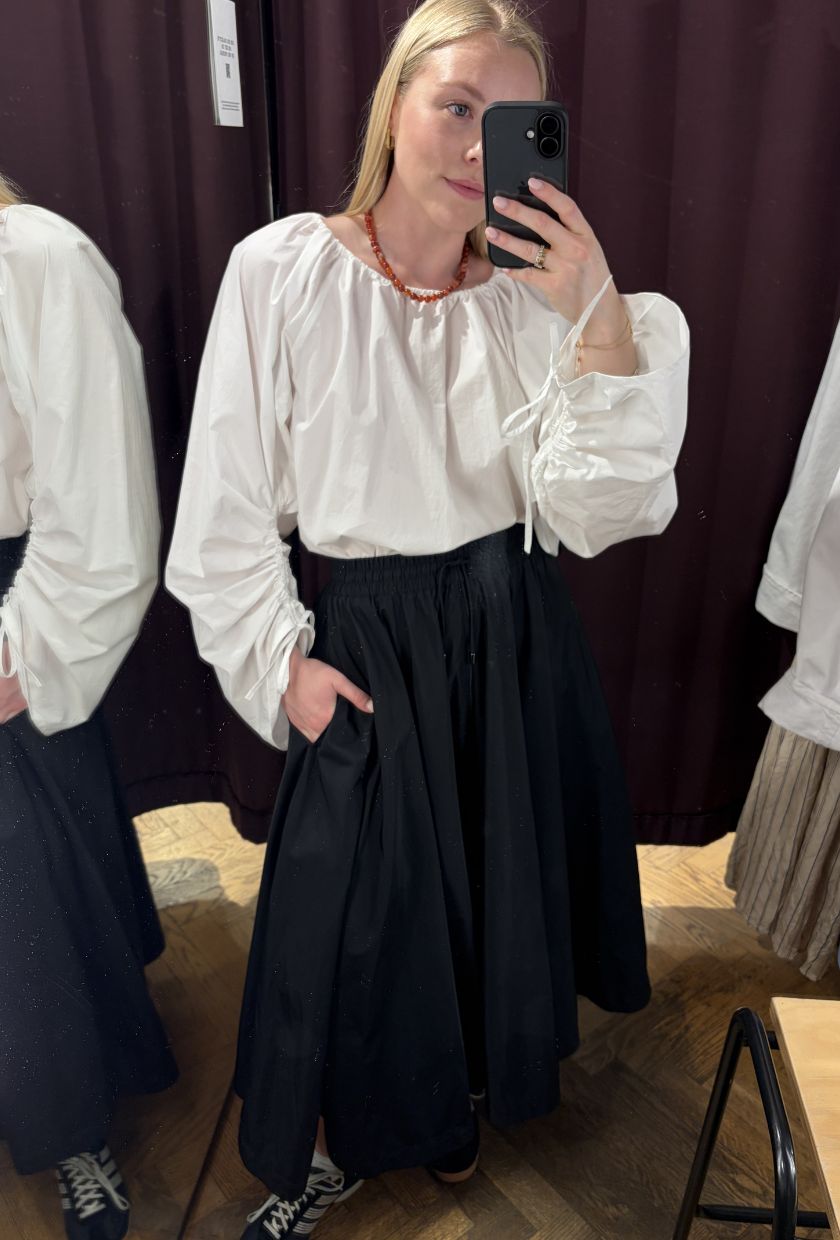 Woman wears white blouse, black midi skirt