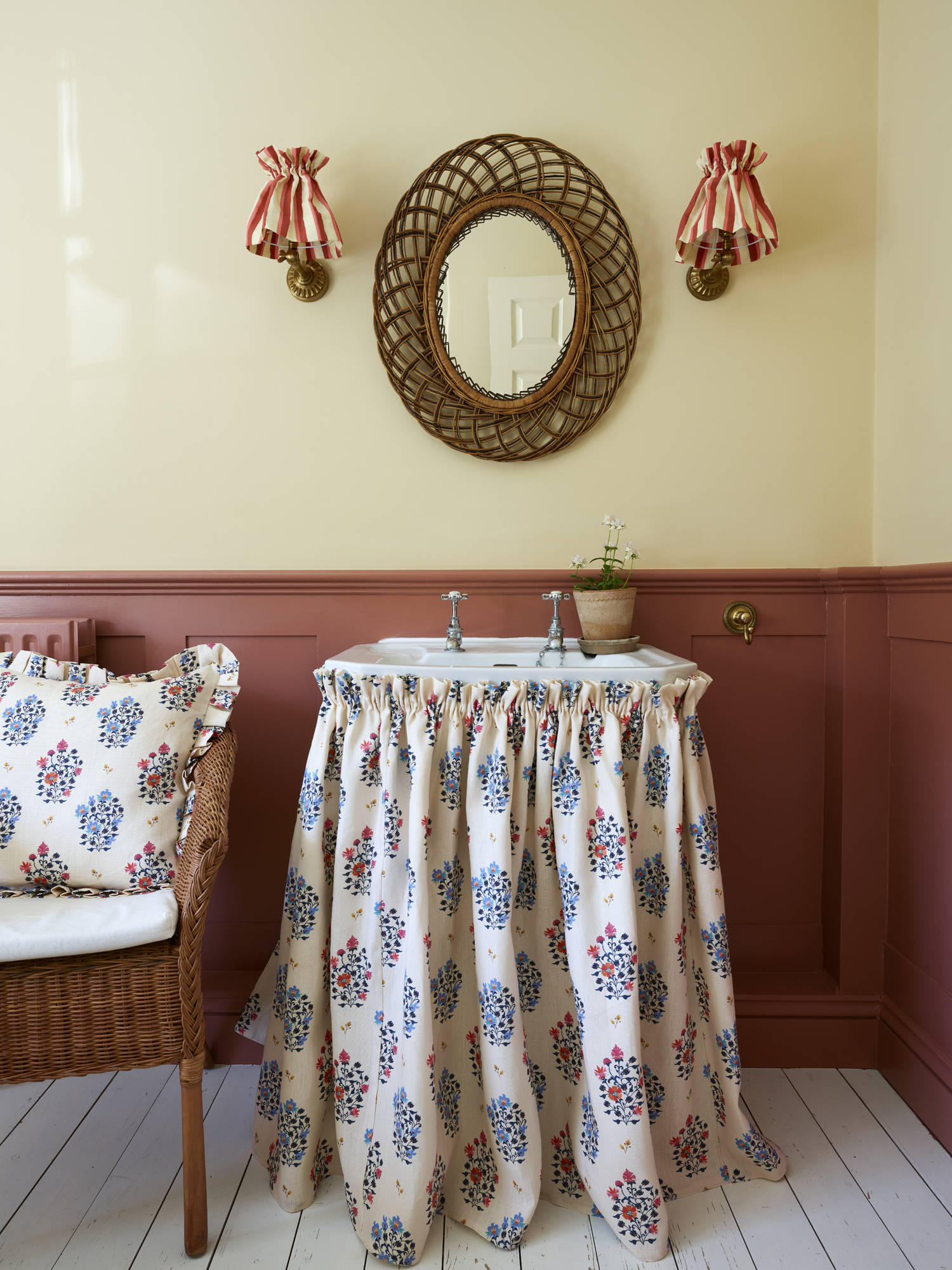 bathroom sink with yellow and red walls and patterned fabric around the sink base
