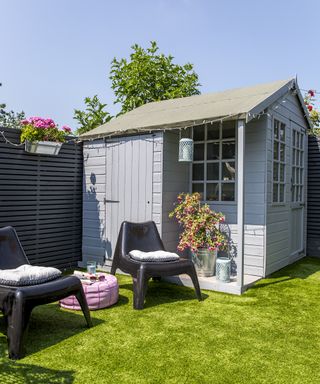 A grey garden building with separate side storage for tools