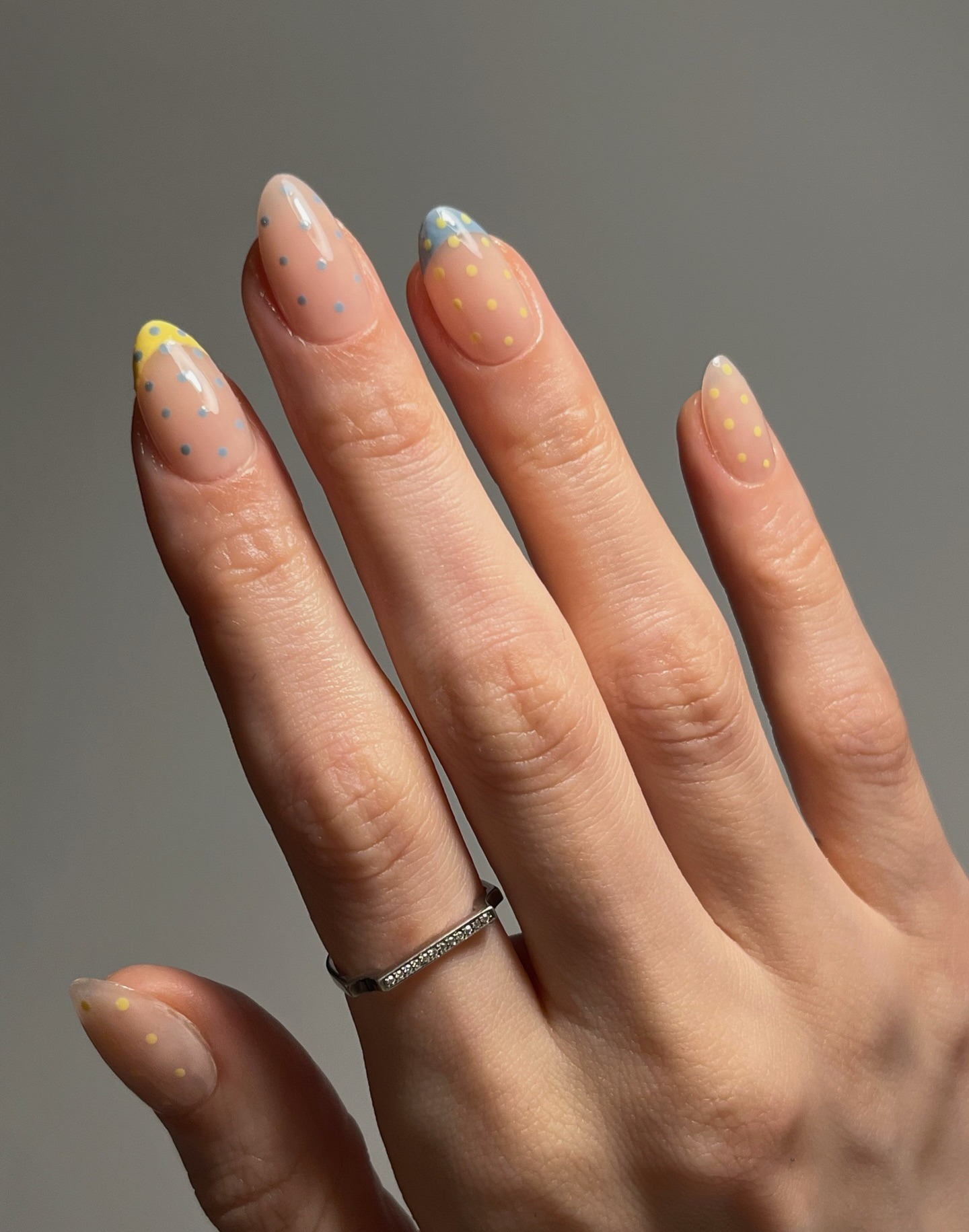 A blue and yellow polka dot French tip manicure