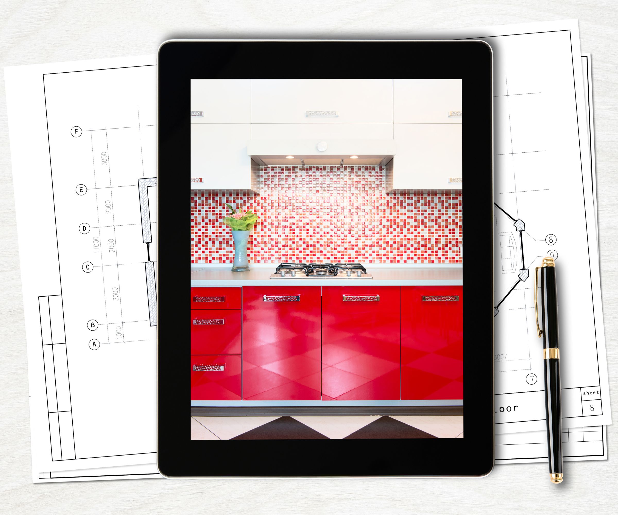 A tablet rests on architectural drawings beside a black and gold pen. On its screen is a modern kitchen with glossy red cabinets, silver handles and a red mosaic tiled splashback.
