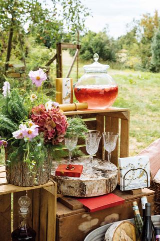 drinks station at backyard wedding with rustic crate log and flowers