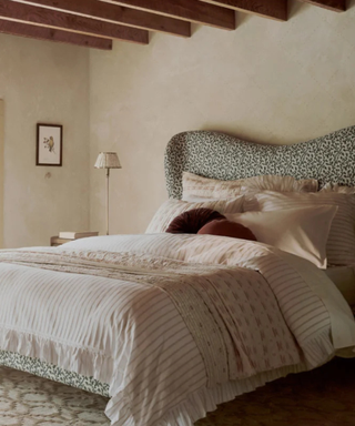 bed with patterned sheets, pillows, and headboard