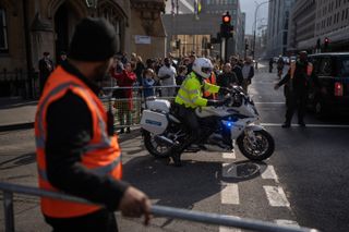 A police motorcycle escorts a vehicle through a security barricade near Westminster Abbey on May 04, 2023 in London, England. The Coronation of King Charles III and The Queen Consort will take place on May 6, part of a three-day celebration