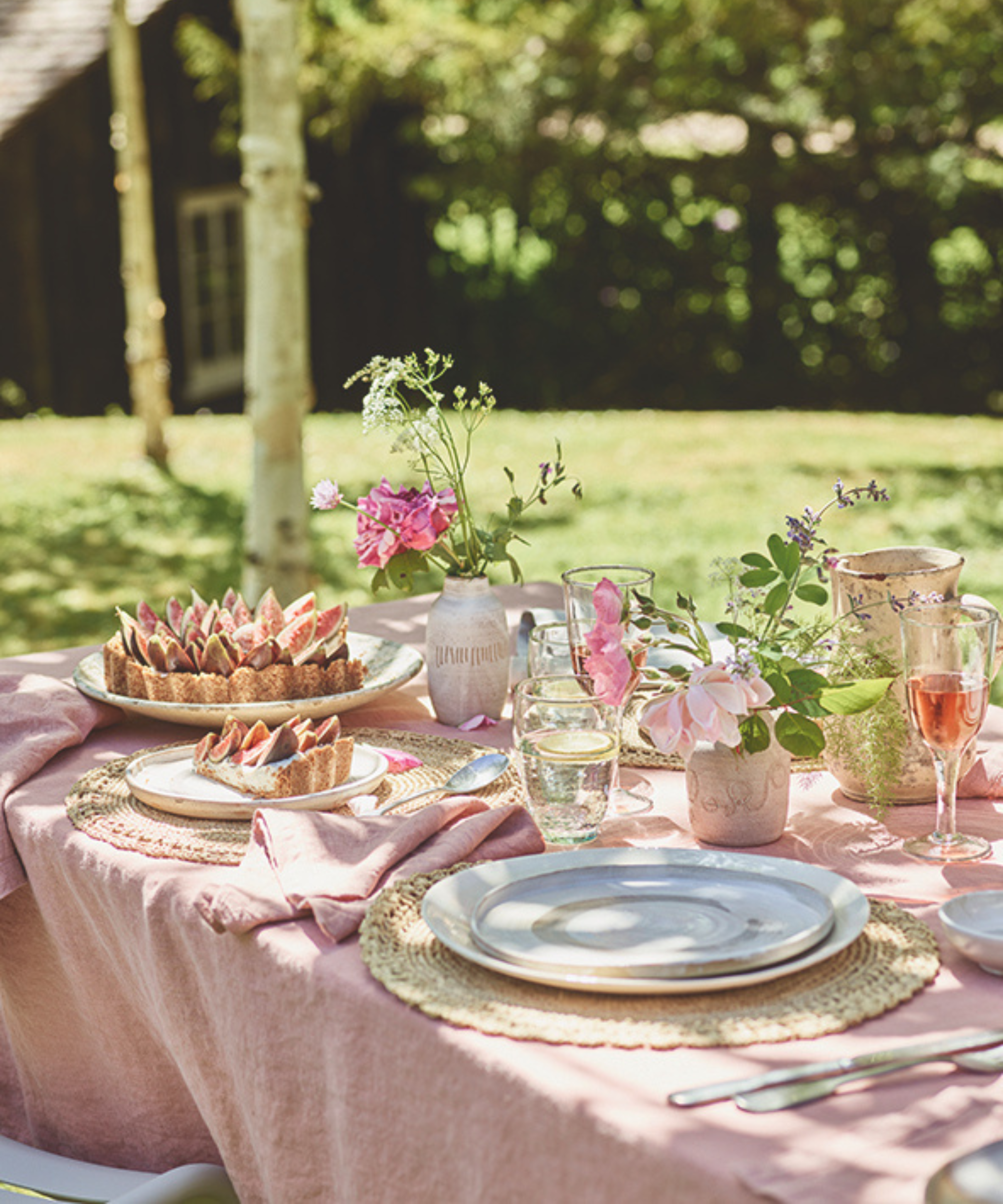 a dining table with a pink tablecloth, flowers, and cake