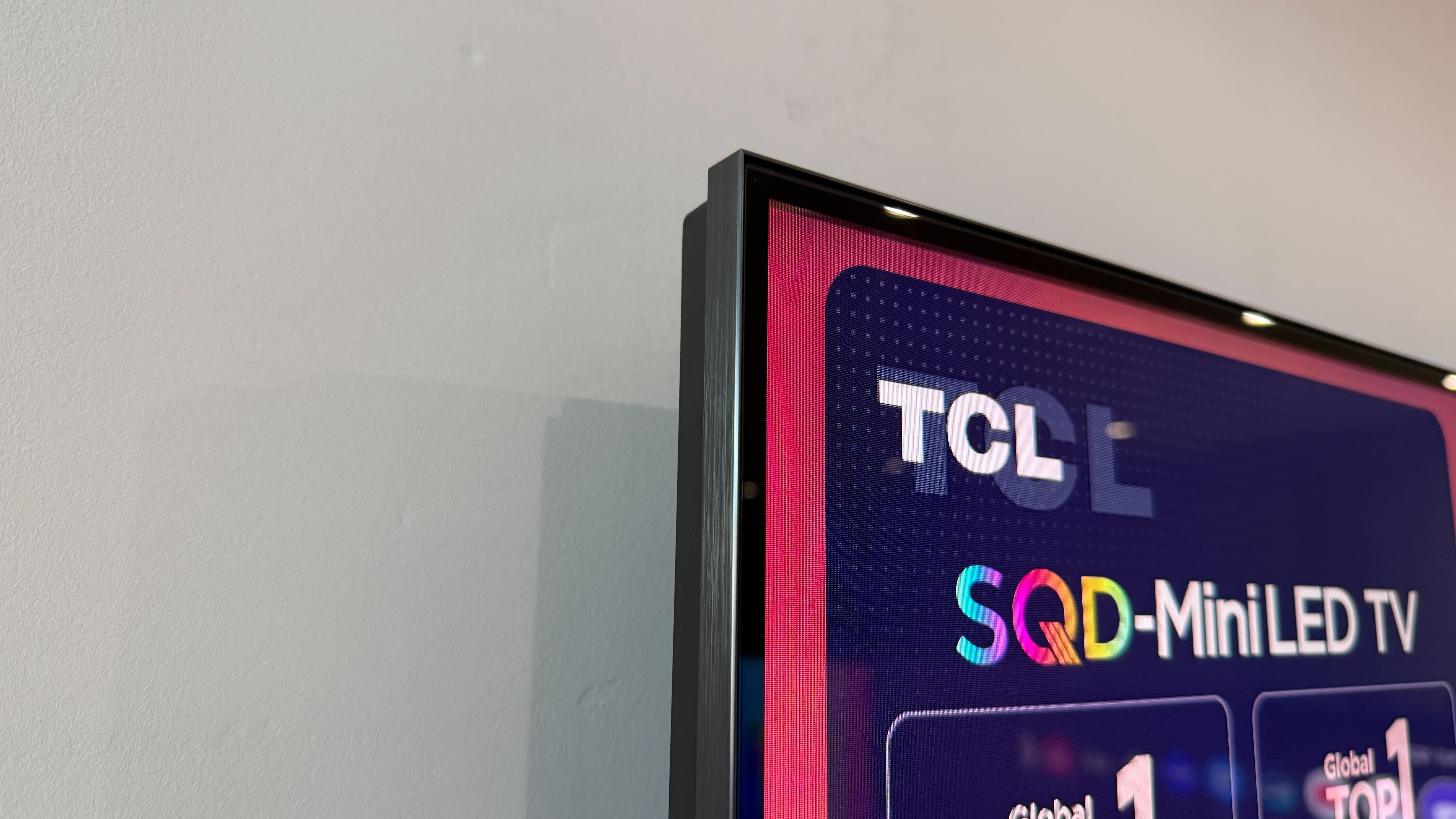 Wall-mounted TCL C7L with vibrant demo content on screen