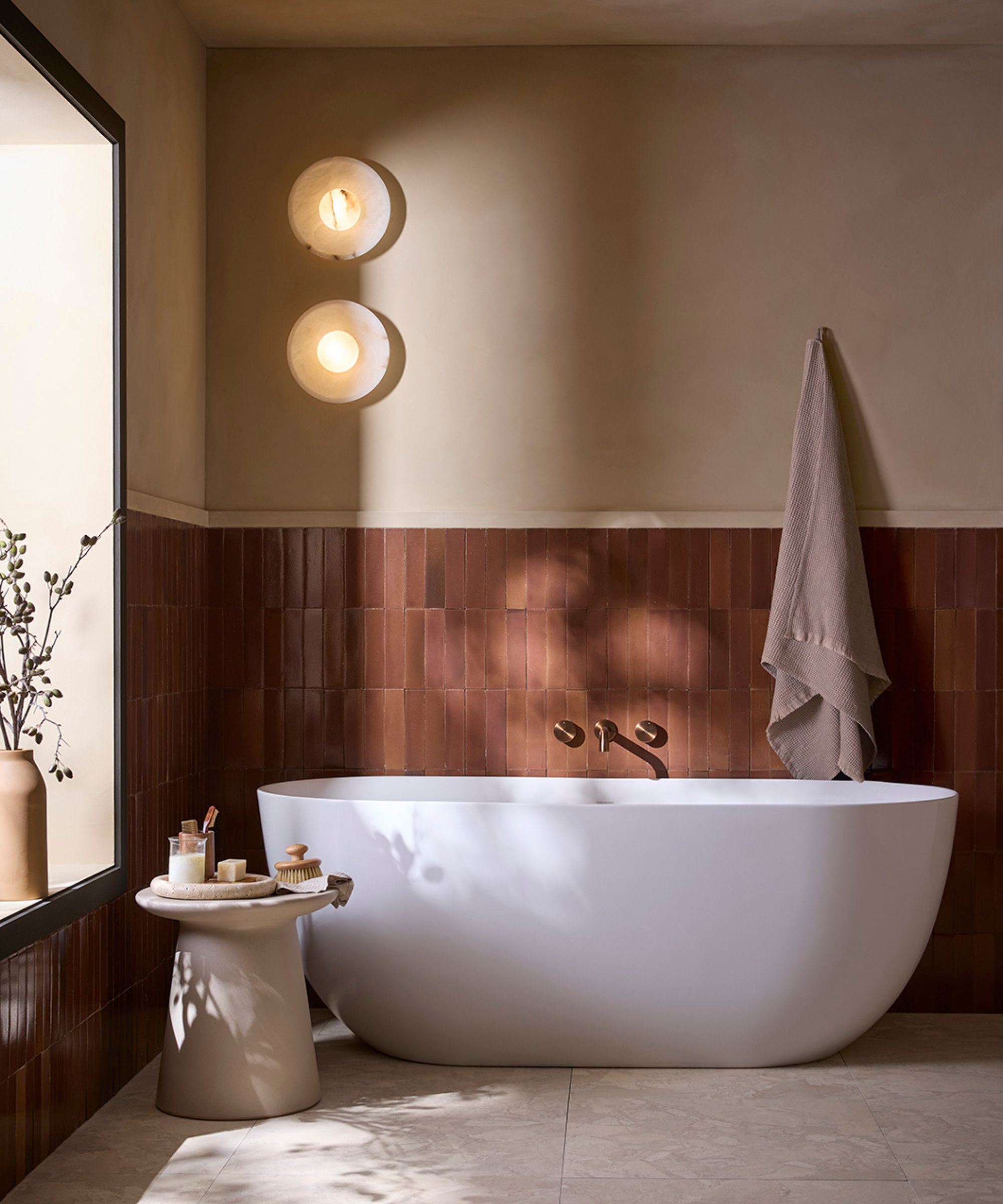 A warm neutral bathroom with rusty red wall tiles