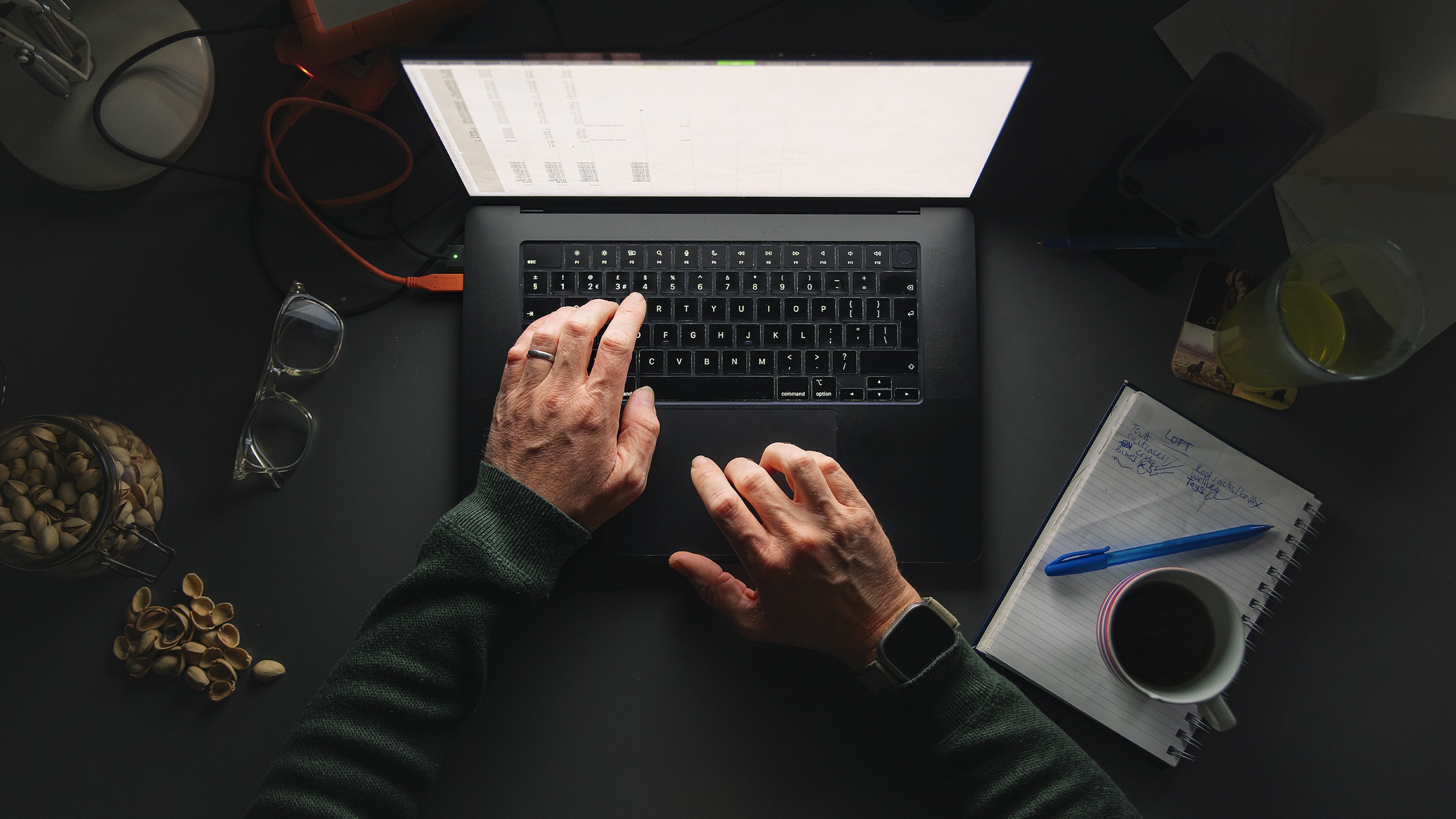 An older man's hands on the keyboard of a laptop.