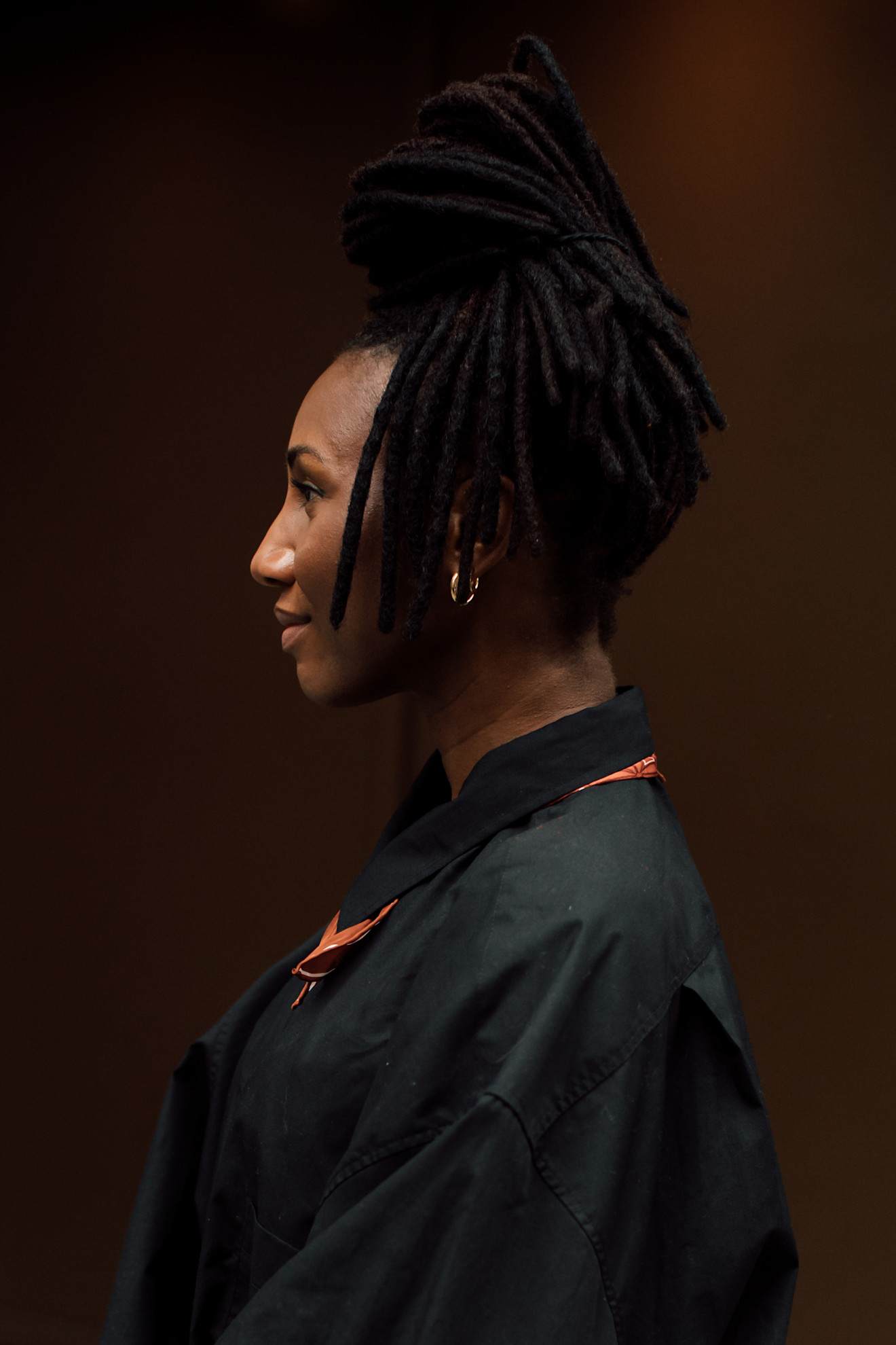 a woman shot in profile in a black shirt with a braided updo