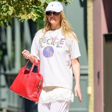 Jennifer Lawrence steps out in New York styling 3/4 length lace-trim trousers with a lace top and an oversized graphic tee. She styled her look with a red handbag and tan toe sandals.
