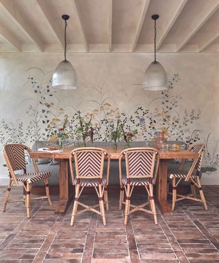 Dining room with painted floral mural in background and terracotta tiled floors and bistro chairs