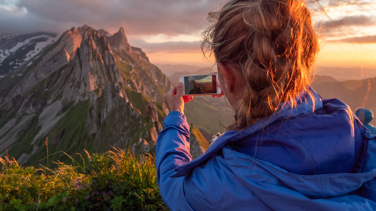 Woman taking photo on top of a mountain