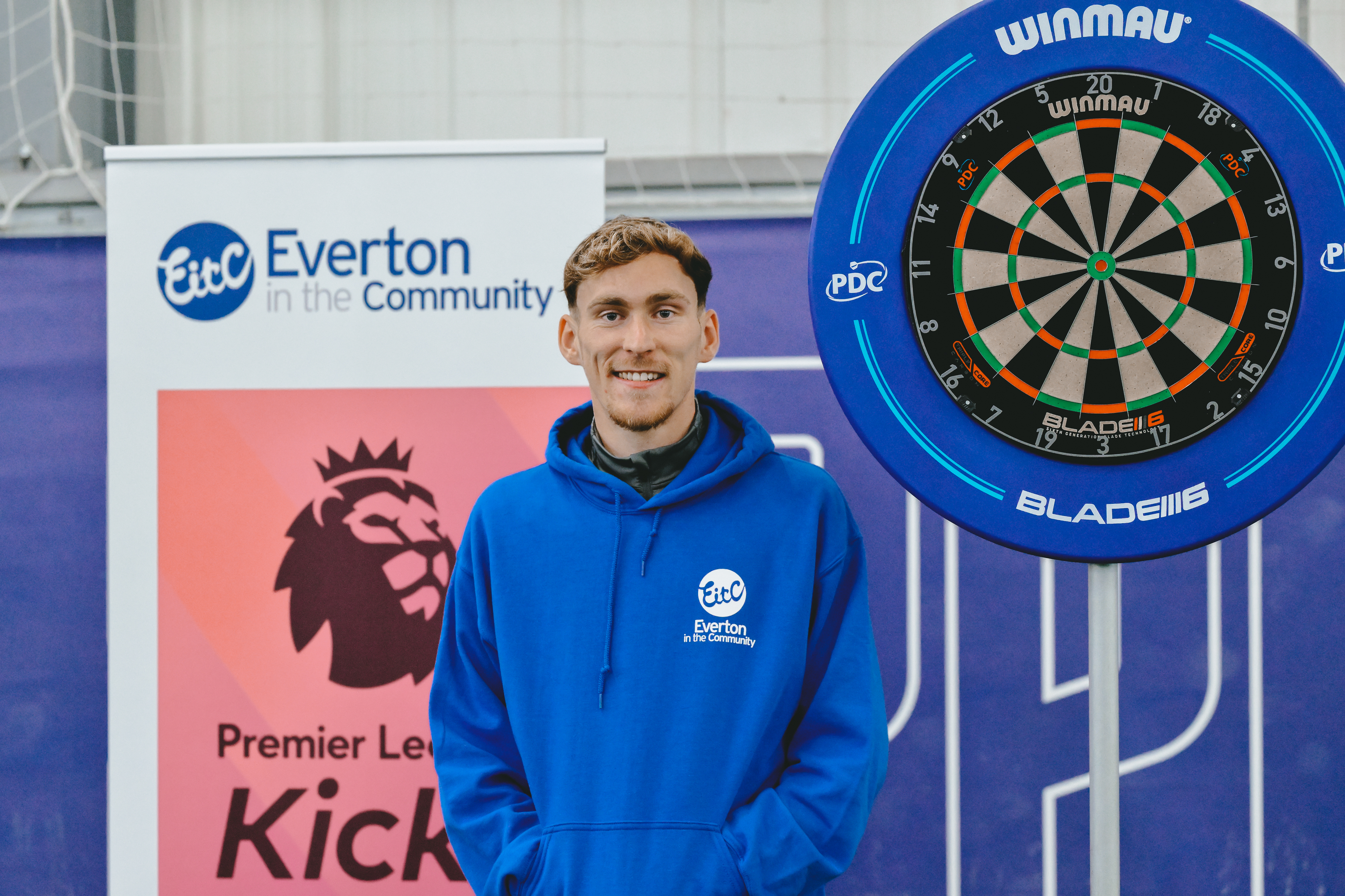 James Garner plays darts with Everton fans at Finch Farm during an Everton in the Community event