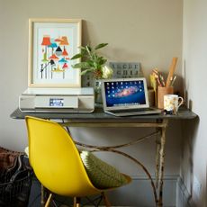 room with white wall and desk with laptop and yellow chair with cushion