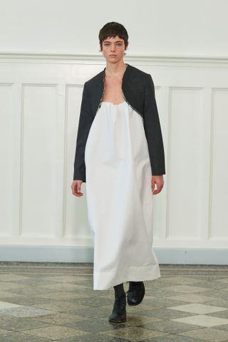 Woman on Mark Kenly Domino Tan runway wearing white dress and jacket