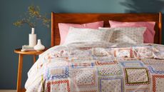 White, red, and pink bedding on a bed against a teal wall. 