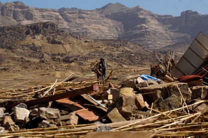 A man in Yemen examines a house leveled by an air raid