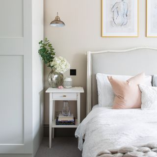 White bedroom with modern country bed with grey headboard and white shaker side table
