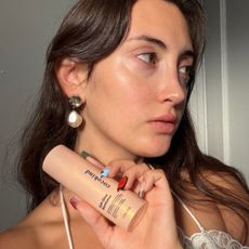 An image of WWW associate beauty editor Alyssa Brascia holding the new Cocokind Soft-Glow Illuminator.