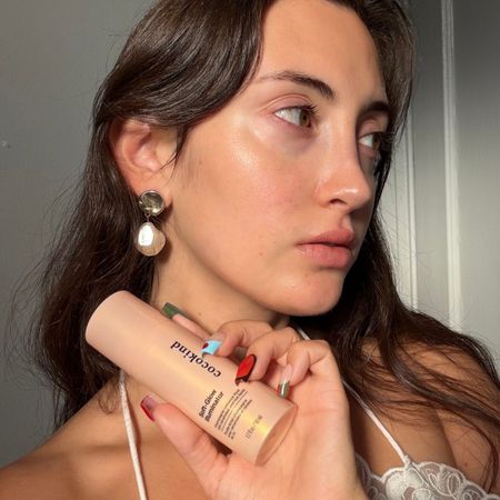 An image of WWW associate beauty editor Alyssa Brascia holding the new Cocokind Soft-Glow Illuminator.
