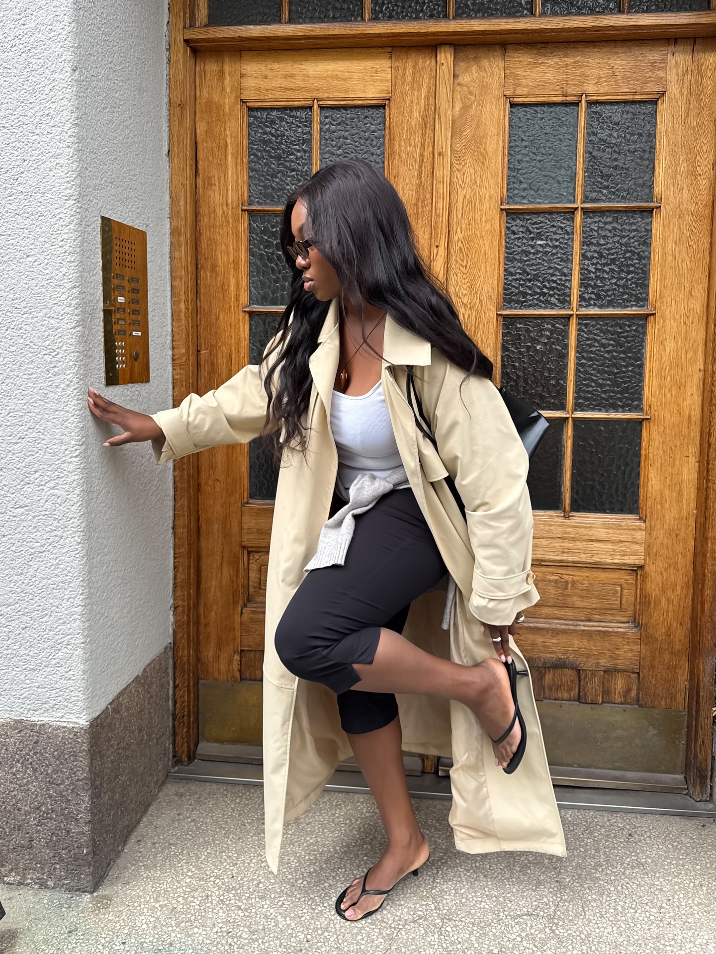 An image of @nnennaechem showcasing how to wear pedal pushers with a trench coat and heeled flip-flops.
