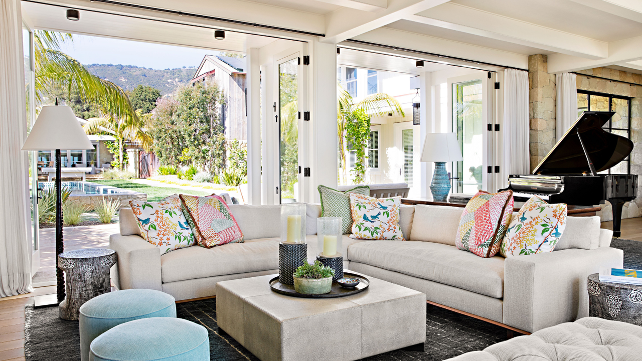 living room with white sofas and blue footstools with french windows