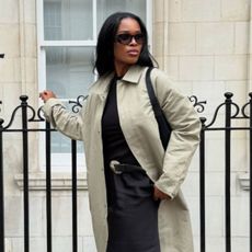 @nlmarilyn wears a light green car coat, black top, satin skirt and black heels