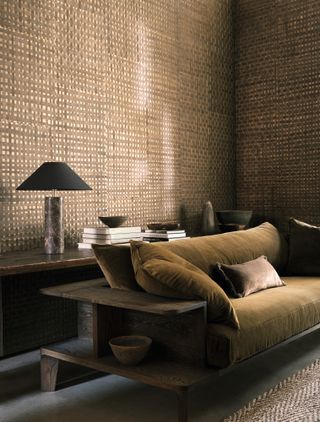 Textured brown wallcovering in a living room with an olive green velvet sofa and built-round shelving